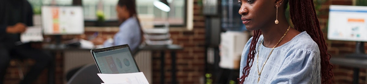 Una mujer sentada en un escritorio en una oficina, revisando el papeleo